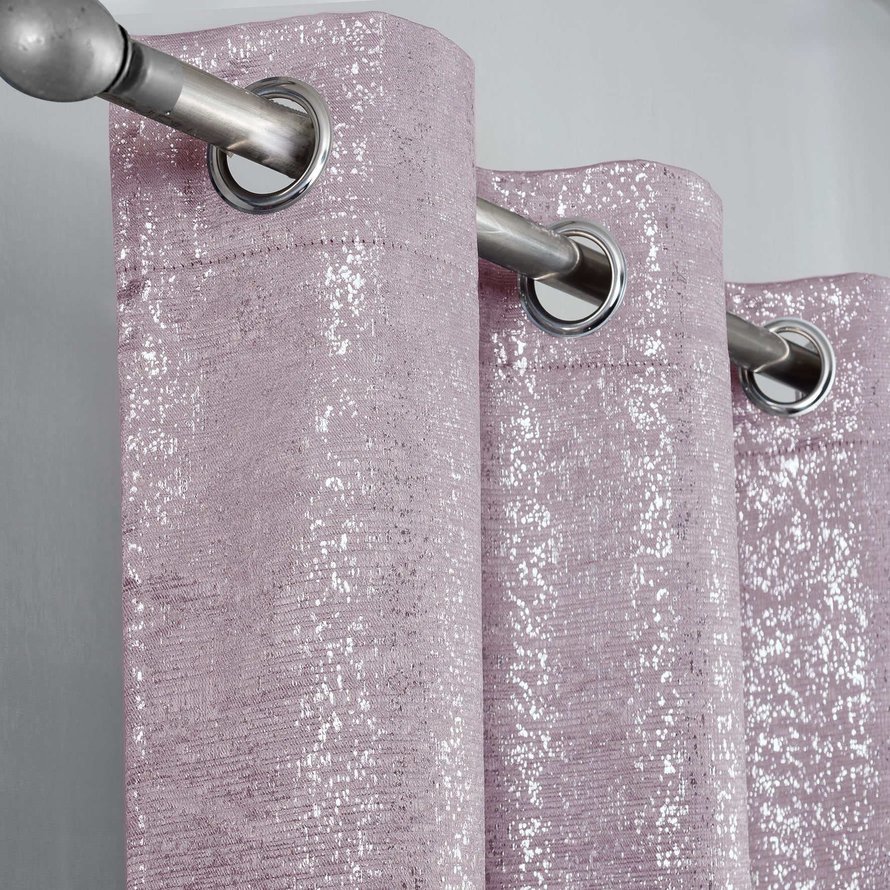 Glittery pink curtain with silver eyelets on a gray background